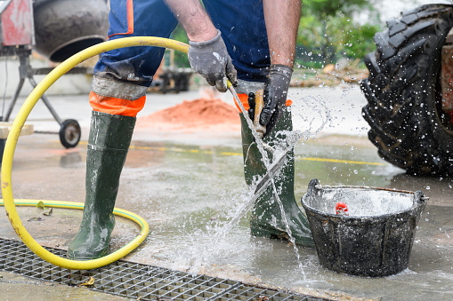 Construction worker washing tools at construction site road street project. Repair, house.